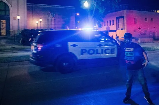 A demonstrator antagonizes a passing police vehicle on August 26, 2020 in Kenosha, Wisconsin. As the city declared a state of emergency curfew, a fourth night of civil unrest occurred after the shooting of Jacob Blake, 29, on August 23. Video shot of the incident appears to show Blake shot multiple times in the back by Wisconsin police officers while attempting to enter the drivers side of a vehicle. The 29-year-old Blake was undergoing surgery for a severed spinal cord, shattered vertebrae and severe damage to organs, according to the family attorneys in published accounts. (Photo by Brandon Bell/Getty Images)