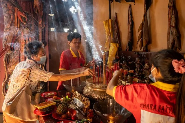 Chinese-Indonesian women burn incense during the Chinese New Year celebration on January 22, 2023 in Denpasar, Bali, Indonesia. Overseas Chinese in Southeast Asia are celebrating the Lunar New Year now that COVID-19 restrictions have been lifted. People traditionally visit relatives and participate in family celebrations during this time. Ethnic Chinese families in Indonesia celebrated the Year of the Rabbit by visiting temples on January 22. The Balis-Chinese community believes that performing the dragon dance, the lion dance known as Barong Sai, and making offerings to the invisible world will protect the community from disaster and keep the visible and invisible worlds in harmony. (Photo by Agung Parameswara/Getty Images)