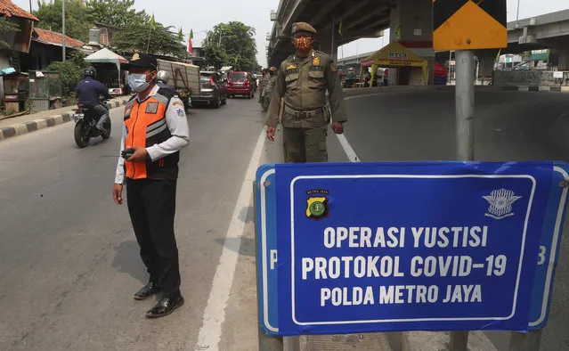 Officers stand guard at a police check point as the large-scale restriction is imposed to curb the spread of the coronavirus outbreak in Jakarta, Indonesia, Monday, September 14, 2020. Indonesia's capital on Monday begins to reimpose large-scale social restrictions to control a rapid expansion in the virus cases. (Photo by Achmad Ibrahim/AP Photo)