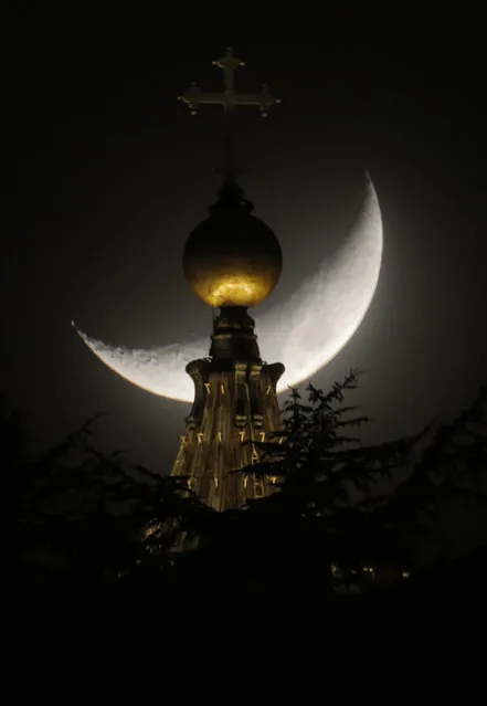 The moon is seen behind a dome of St. Peter's Basilica at the Vatican, Saturday, March 16, 2013. Pope Francis offered intimate insights Saturday into the moments after his election, telling journalists that he was immediately inspired to take the name of St. Francis of Assisi because of his work for peace and the poor – and that he himself would like to see “a poor church and a church for the poor”. (Photo by Dmitry Lovetsky/AP Photo)