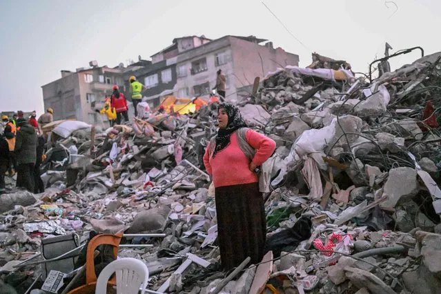 A woman stands in the rubble hoping her relatives to be found by rescuers in Hatay on February 13, 2023, as rescue teams began to wind down the search for survivors today, a week after an earthquake devastated parts of Turkey and Syria leaving more than 35,000 dead and millions in dire need of aid. (Photo by Bulent Kilic/AFP Photo)