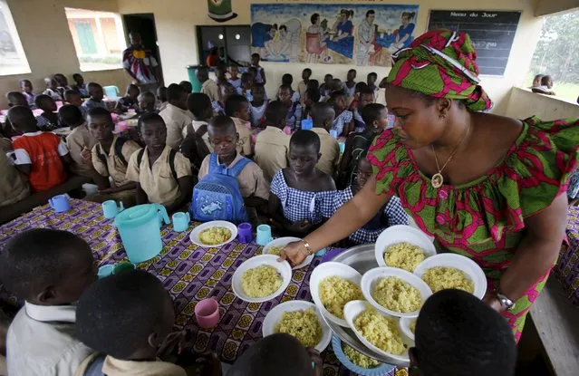Students wait to eat at a school canteen, on  wall reading "Eating well to learn better" in N'zikro, Aboisso, Ivory Coast, October 27, 2015. (Photo by Thierry Gouegnon/Reuters)