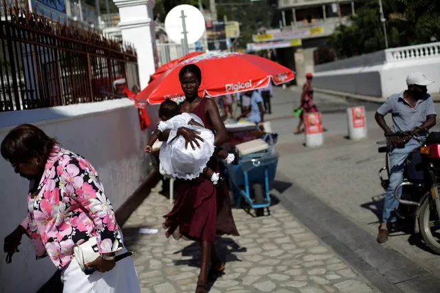 A woman carrying a baby arrives for mass at Notre Dame cathedral in Cap Haitien, Haiti, September 18, 2016. (Photo by Andres Martinez Casares/Reuters)