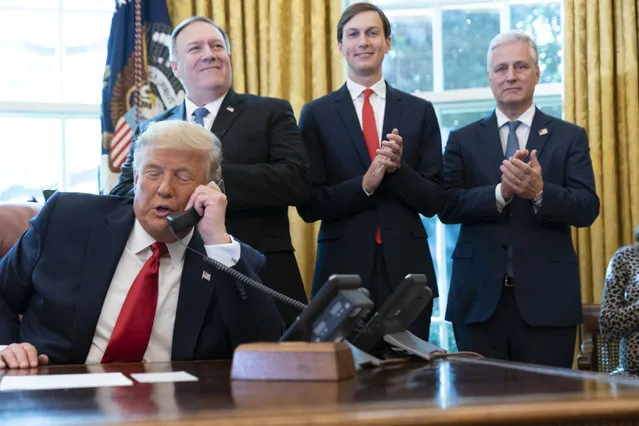 President Donald Trump talks on a phone call with the leaders of Sudan and Israel, as Secretary of State Mike Pompeo, left, White House senior adviser Jared Kushner, and National Security Adviser Robert O'Brien, applaud in the Oval Office of the White House, Friday, October 23, 2020, in Washington. (Photo by Alex Brandon/AP Photo)
