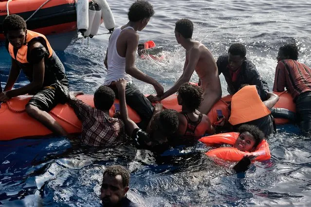 Migrants wait to be rescued by members of Proactiva Open Arms NGO in the Mediterranean Sea, some 12 nautical miles north of Libya, on October 4, 2016. At least 1,800 migrants were rescued off the Libyan coast, the Italian coastguard announced, adding that similar operations were underway around 15 other overloaded vessels. (Photo by Aris Messinis/AFP Photo)