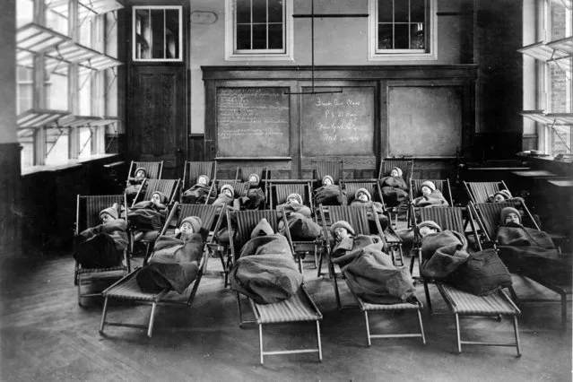 This 1911 photo from the Library of Congress shows children wrapped in blankets, at a fresh air class rest hour at Public School No. 51, in New York. Poor ventilation in school buildings across the U.S. will limit the ability of in-person instruction to resume safely. Some districts are warming to the idea of outdoor classrooms. (Photo by Library of Congress via AP Photo)