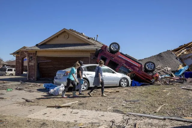 Neighbors walk in front of a home damaged at Wheatland Drive and Conway Drive on Monday, February 27, 2023 in Norman, Okla. The damage came after rare severe storms and tornadoes moved through Oklahoma overnight. (Photo by Alonzo Adams/AP Photo)