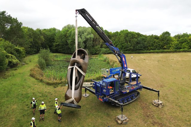 Workers move the monumental bronze sculpture Large Upright Internal/External Form, which stands at 673cm tall, as they continue their refresh of the presentation of outdoor sculptures at Henry Moore Studios & Gardens in Perry Green in Hertfordshire, UK, the home of 20th century sculptor Henry Moore on Monday, August 18, 2025. (Photo by Joe Giddens/PA Images via Getty Images)