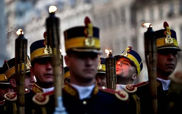 Romanian soldiers of the ceremonial Guard Regiment prepare to march holding burning torches during an event marking Ground Forces Day in Bucharest, on April 23, 2013. (Photo by Vadim Ghirda/Associated Press)