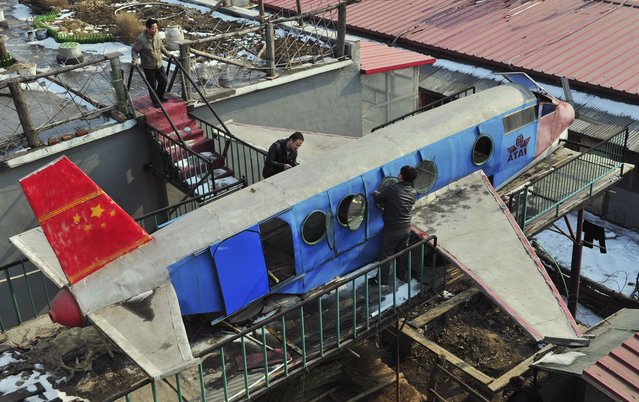 Li Jingchun (top), a 58-year-old farmer, looks on as his family members work on his self-made aircraft on top of his house in Xiahe village located in Shenyang, Liaoning province February 28, 2012. The 5m long, 1.5m wide plane, mostly made of recycled iron plates, cost the aircraft enthusiast and his family two years and more than 40,000 yuan ($6,349), according to local media. (Photo by Sheng Li/Reuters)