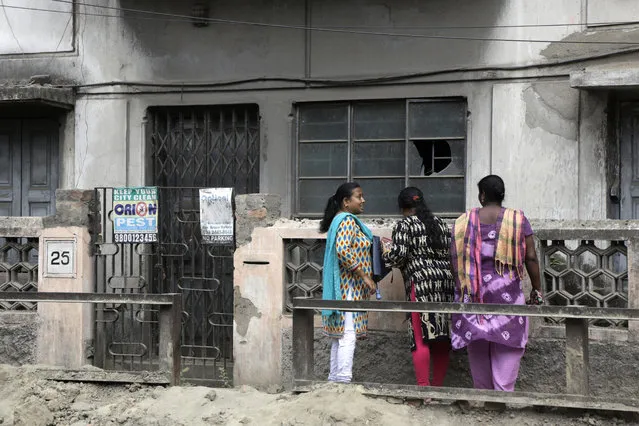 Indian women stand outside the house where a 46-year-old Subhabrata Majumdar had allegedly kept his mother's body in a freezer for almost three years while collecting her monthly pension payments in Kolkata, India, Friday, April 6, 2018. Police officer Nilanjan Biswas says Majumdar was arrested after his mother's body was found in the large freezer during a Thursday police raid on their home in the city of Kolkata. (Photo by Bikas Das/AP Photo)