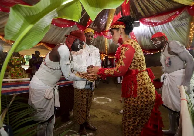 Winti spiritual leader Ramon Mac-Nack (2nd L) looks on as as his bride Melissa Karwafodi (2nd R) hands a gourd to a Maroon priest (L) as they are wedded in the first Winti marriage ever to be held in public, in district Para, Suriname, November 16, 2015. (Photo by Ranu Abhelakh/Reuters)