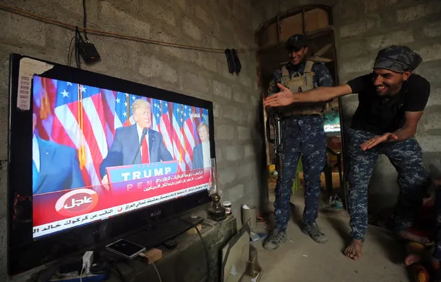 Members of the Iraqi forces react as they watch Donald Trump giving a speech after he won the US president elections in the village of Arbid on the southern outskirts of Mosul on November 9, 2016, as they rest in a house during the ongoing military operation to retake Mosul from the Islamic State (IS) group. Iraqi Prime Minister Haider al-Abadi congratulated Donald Trump on his election as president and said he hoped for continued US and international support in the war against jihadists. (Photo by Ahmad Al-Rubaye/AFP Photo)