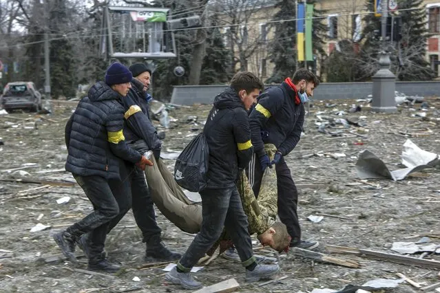 Ukrainian volunteers carry a victim out of the City Hall building, following shelling in Kharkiv, Ukraine, Tuesday, March 1, 2022. Russia on Tuesday stepped up shelling of Kharkiv, Ukraine's second-largest city, pounding civilian targets there. Casualties mounted and reports emerged that more than 70 Ukrainian soldiers were killed after Russian artillery recently hit a military base in Okhtyrka, a city between Kharkiv and Kyiv, the capital. (Photo by Pavel Dorogoy/AP Photo)