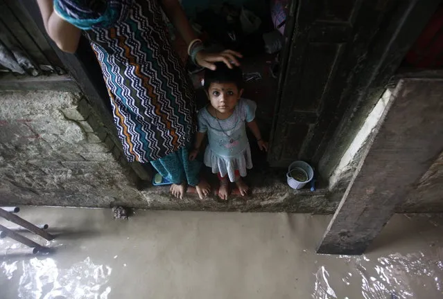 A child watches while standing on the doorstep of her house next to a flooded alley due to rising water level of river Yamuna after heavy monsoon rains in New Delhi June 18, 2013. The rains are at least twice as heavy as usual in northwest and central India as the June-September monsoon spreads north, covering the whole country a month faster than normal. (Photo by Anindito Mukherjee/Reuters)