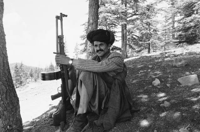An Afghan rebel, armed with a light machine gun, rests after firing practice at the Khanday Khula rebel camp in Pakistan, near the Afghan border, June 30, 1980. (Photo by AP Photo)