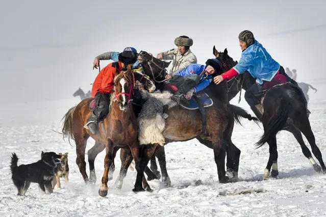 Kyzgyz horse riders compete during a kok boru, also called ulak tartysh, a traditional game in which players on horseback manoeuvre with a goat's carcass and score by putting it into the opponents' goal outside Tash-Dobo village, 15 kilometers (9,4 Miles) south of Bishkek, Kyrgyzstan, Saturday, December 12, 2020. The game has its origins in the distant past, when men went to hunt wolves that attacked their livestock, picking up running wolves from the ground and throwing them between each other almost playfully. The game today requires teams to throw a dead sheep or goat into their opponent's well on the playing field. (Photo by Vladimir Voronin/AP Photo)