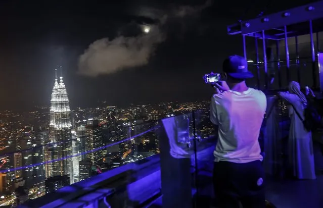 A tourist takes a photograph of the Kuala Lumpur night scene using his mobile phone during the supermoon night at Kuala Lumpur Tower in Kuala Lumpur, Malaysia, 14 November 2016. November 14 will see the largest full moon since 1948, also known as supermoon, when the moon reaches its closed point to Earth and becomes full at 8:52 AM EST, 13:52 UTC on 14 November. The next time the moon will be this close will be on 25 November 2034. (Photo by Ahmad Yusni/EPA)