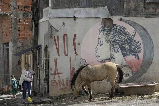 In this May 20, 2018 photo, a woman sweeps the sidewalk in the Jardim Peri neighborhood where professional soccer player Gabriel Jesus grew up, in Sao Paulo, Brazil. The neighborhood is such a big part of Gabriel Jesus that he tattooed the favela on his right arm. (Photo by Andre Penner/AP Photo)