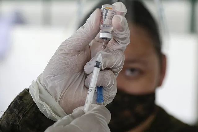 An army doctor prepares to inject the Sinovac vaccine from China during a vaccination at Fort Bonifacio, Metro Manila, Philippines on Tuesday, March 2, 2021. The Philippines launched a vaccination campaign to contain one of Southeast Asia's worst coronavirus outbreaks but faces supply problems and public resistance, which it hopes to ease by inoculating top officials. (Photo by Aaron Favila/AP Photo)