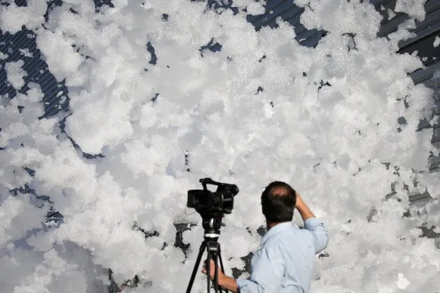 A TV cameraman films fire retardant foam blowing in the wind after a fire alarm malfunctioned in a hangar according to local media, near the San Jose airport in Santa Clara, California, U.S. November 18, 2016. (Photo by Elijah Nouvelage/Reuters)
