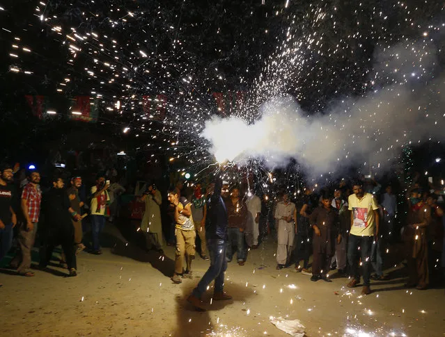 A supporter of Pakistani politician Imran Khan, chief of Pakistan Tehreek-e-Insaf party, releases fireworks to celebrate projected unofficial results announced by television channels indicating their candidates' success in the parliamentary elections in Islamabad, Pakistan, Thursday, July 26, 2018. (Photo by Anjum Naveed/AP Photo)