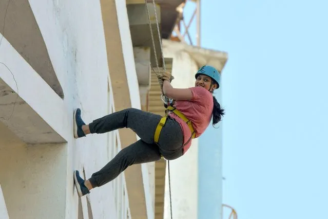 A youth rappels down the face of the Kanteerava Outdoor Stadium as part of a program held on the occasion of International Women's Day, in Bangalore on March 8, 2021. (Photo by Manjunath Kiran/AFP Photo)