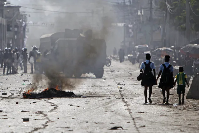 Students walk on a street after supporters of presidential candidate Maryse Narcisse from Fanmi Lavalas political party clashed with the police in Port-au-Prince, Haiti, Tuesday, November 22, 2016. For a second straight day, partisans with a Haitian political faction hurled rocks at police and burned tires to demand “fair” election results they insist will put their candidate in the presidency. (Photo by Ricardo Arduengo/AP Photo)