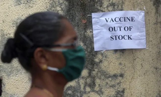A woman wearing mask walks past a notice about the shortage of coronavirus (COVID-19) vaccine supply outside a vaccination centre in Mumbai, India, Thursday, April 8, 2021. India started its vaccination drive in January. So far, more than 90 million Indians above 45 and health workers have received at least one shot and only 11 million of them have got both. (Photo by Rafiq Maqbool/AP Photo)