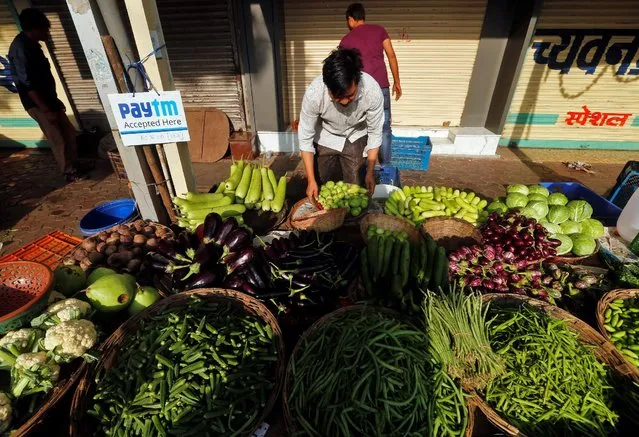 An advertisement board of Paytm, a digital wallet company, is seen placed at a roadside vendor's stall as he arranges vegetables in Mumbai, India, November 19, 2016. (Photo by Shailesh Andrade/Reuters)