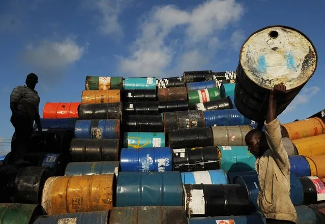 Men stack oil barrels at a depot in Santo Domingo February 6, 2015. A group of resident Haitians sell the metal barrels for $9 each to be used as garbage bins, or made into grills or to store water. (Photo by Ricardo Rojas/Reuters)