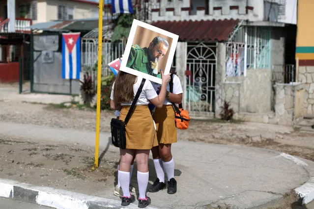 School girls hold a photograph of Cuba's former President Fidel Castro as they wait for Castro's ashes to pass during a three-day journey to the eastern city of Santiago de Cuba, in Buenaventura, Cuba, December 2, 2016. (Photo by Alexandre Meneghini/Reuters)