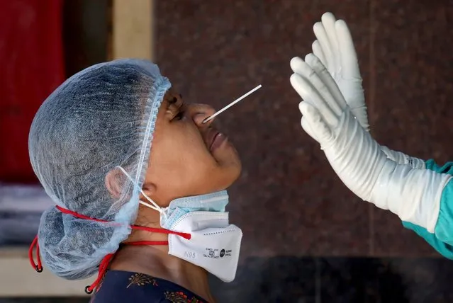 A woman reacts as a healthcare worker takes a nasal swab sample for a coronavirus disease (COVID-19) test at a government-run hospital, amidst the spread of the disease in Kolkata, India, May 6, 2021. (Photo by Rupak De Chowdhuri/Reuters)