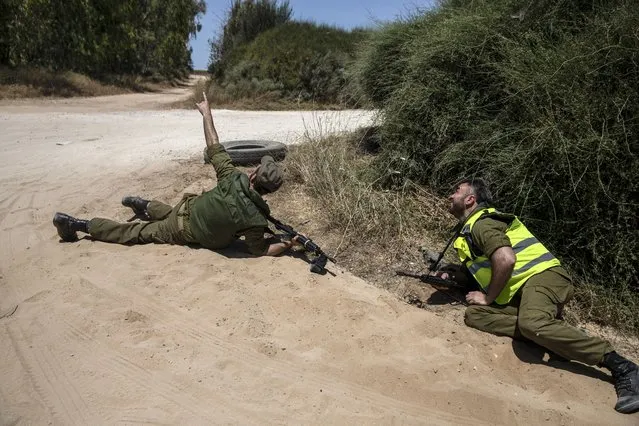 Israeli soldiers take cover on the ground as a siren sounds a warning of incoming rockets fired from the Gaza Strip, near the Israeli-Gaza border, in southern Israel, Monday, May 17, 2021. (Photo by Heidi Levine/AP Photo)