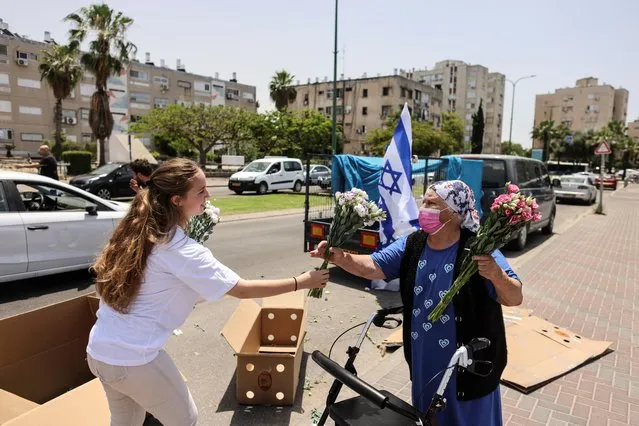 An Israeli woman offers flowers to an elderly by a shopping centre in Ashkelon following Israel-Hamas truce, in Ashkelon, Israel on May 21, 2021. (Photo by Ronen Zvulun/Reuters)