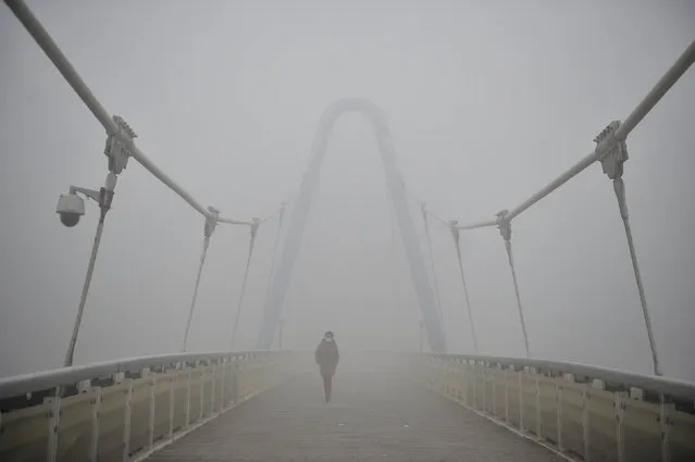 A woman wearing a mask walks along a bridge in smog during a polluted day in Tianjin, China, December 19, 2016. (Photo by Reuters/Stringer)