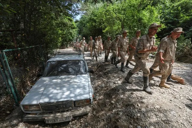 Russian military personnel walks past a car partly buried by flooding after heavy rainfall in Yalta, Crimea on June 22, 2021. (Photo by Alexey Pavlishak/Reuters)