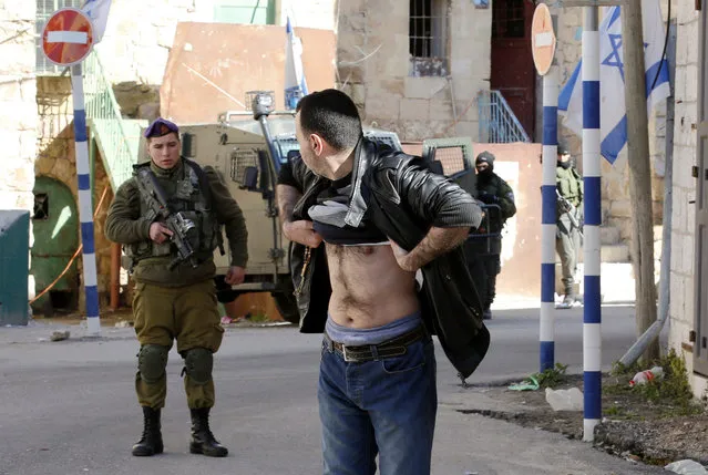 An Israeli army soldier orders a Palestinian to lift his clothes for searching near the Ibrahimi mosque in the West Bank city of Hebron, 03 February 2016. Israeli army soldiers searched Palestinians who passed in front of houses which Israeli settlers try to take over. (Photo by Abed Al Hashlamoun/EPA)