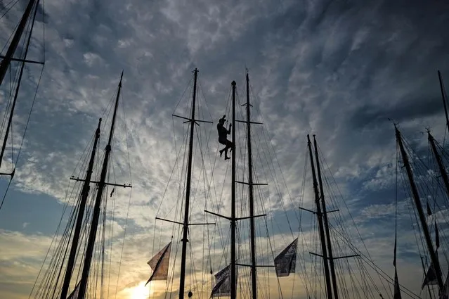 A crew member climbs the mast of a yacht in Saint Tropez, southern France, on October 4, 2023, as part of the annual “Les Voiles de Saint-Tropez” event. Around a hundred yachts will take part in regattas in the bay of Saint-Tropez during the event. (Photo by Valery Hache/AFP Photo)