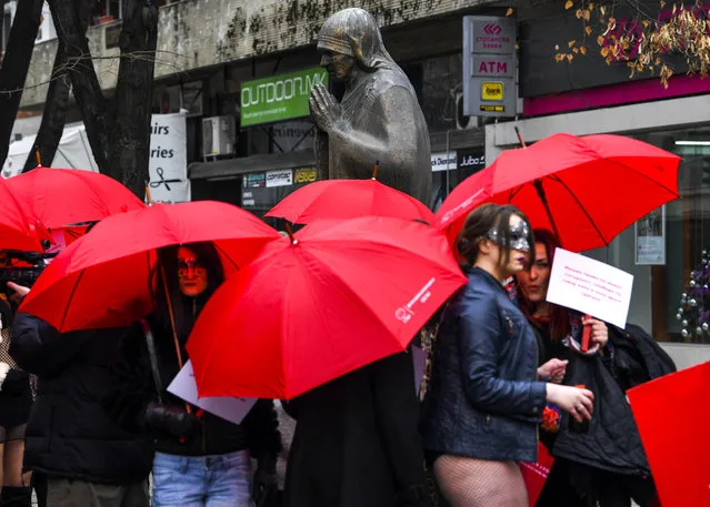 Macedonian s*x workers carrying red umbrellas stay around the monument of Mother Thereza, before a rally to mark the International Day to End Violence Against s*x Workers in Skopje, The Former Yugoslav Republic of Yugoslavia, 17 December 2018. (Photo by Georgi Licovski/AFP Photo)
