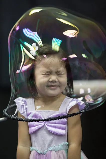 A girl reacts as she stands in a soap bubble during Spanish artist Pep Bou's Bubble Magic show in Hong Kong, China, 13 September 2016. The world-renowned bubble artist is in Hong Kong to perform eight shows, starting 14 September. (Photo by Jerome Favre/EPA)