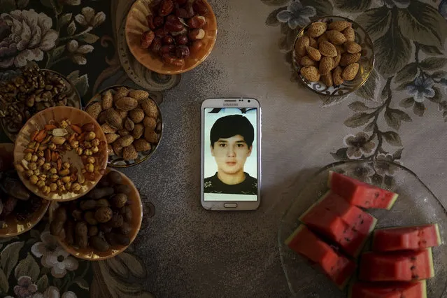 A phone displays an image of Pakzat Qurban, now 18, who was imprisoned in China when he was 16, sits on a table surrounded with plates of watermelon and nuts at the home of his parents in Istanbul, Turkey, on August 24, 2018. Qurban and his family moved to Turkey from in 2015, and Qurban was arrested at a Chinese airport when he went back to visit his grandparents. His parents, Qurbanjan Nurmemet and Gulgine Mehmut, say they received an 8 second video from an officer of their son strapped to a torture chair to try to coerce them to spy for Chinese police. (Photo by Dake Kang/AP Photo)