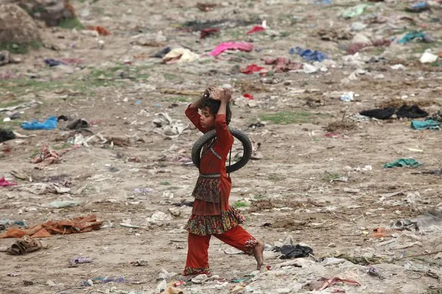 A girl carries a broken brick on her head while walks along a littered ground in Lahore's slum, February 16, 2015. (Photo by Mohsin Raza/Reuters)