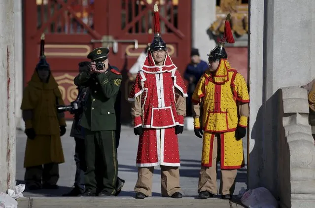 A paramilitary policeman takes photographs next to his colleagues, dressed as soldiers from the Qing Dynasty, during a rehearsal for the upcoming temple fair, adapted from an ancient Qing Dynasty ceremony where emperors prayed for good harvest and fortune, to celebrate the upcoming Lunar New Year of the Monkey at Ditan Park (the Temple of Earth), in Beijing, China, February 6, 2016. (Photo by Jason Lee/Reuters)