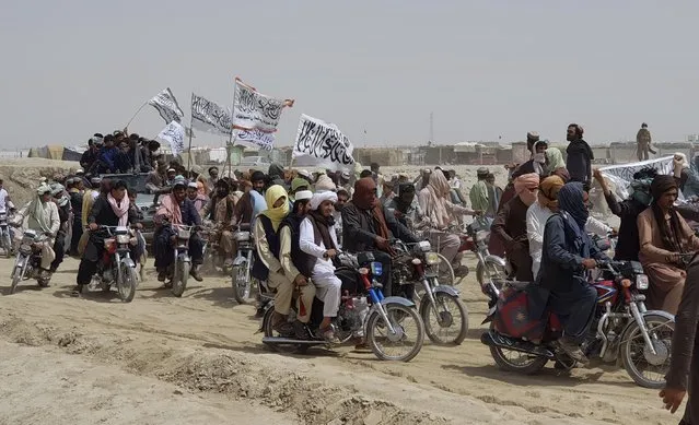 Supporters of the Taliban carry the Taliban's signature white flags in the Afghan-Pakistan border town of Chaman, Pakistan, Wednesday, July 14, 2021. The Taliban are pressing on with their surge in Afghanistan, saying Wednesday that they seized Spin Boldaka, a strategic border crossing with Pakistan – the latest in a series of key border post to come under their control in recent weeks. (Photo by Tariq Achkzai/AP Photo)