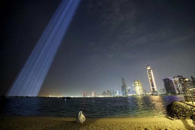 Mexican artist Rafael Lozano-Hemmer's artwork entitled “Collider”, formed by hundreds of pencil-beam robotic searchlights that create a glimmering curtain of light, is visible from al-Lulu Island on the backdrop of the Abu Dhabi downtown on November 20, 2023, during the Manar Abu Dhabi public light art exhibition. (Photo by Giuseppe Cacace/AFP Photo)