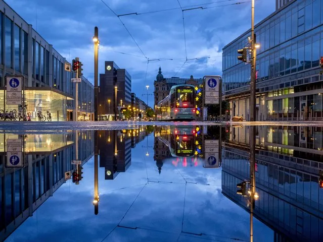 A tram is reflected in a puddle after the city is almost empty shortly after the end of the curfew in central Frankfurt, Germany, Tuesday, May 11, 2021. (Photo by Michael Probst/AP Photo)