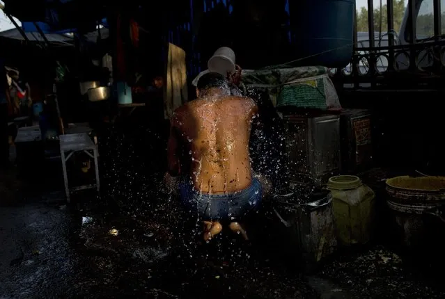 A man who lives in the street takes bath in the morning in the old Delhi area of New Delhi, India, Tuesday, April 14, 2015. The four-century-old neighborhood is chaotic and crowded, yet is the vibrant heart of the city. (Photo by Bernat Armangue/AP Photo)