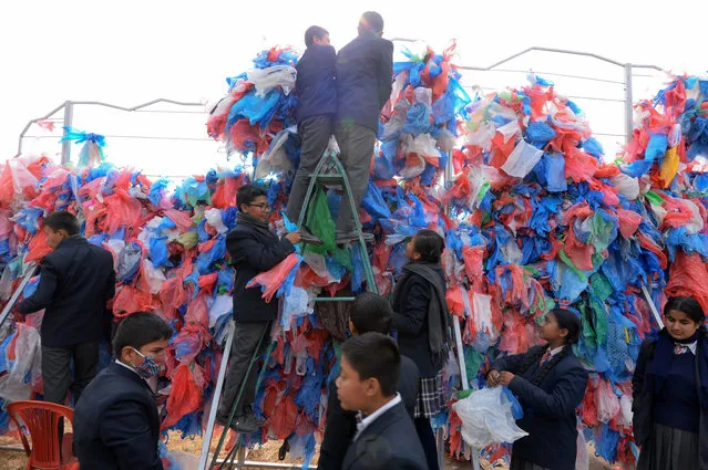 Nepali volunteers and school children tie up recycled plastic bags to make a sculpture representing the Dead Sea in a bid to set a new world record for the largest sculpture made out of recycled plastic bags in Kathmandu on December 5, 2018. Some 100,000 plastic bags were used in the sculpture, in a bid to break the previous record made in 2012 in Singapore using 68,000 plastic bags. (Photo by Prakash Mathema/AFP Photo)