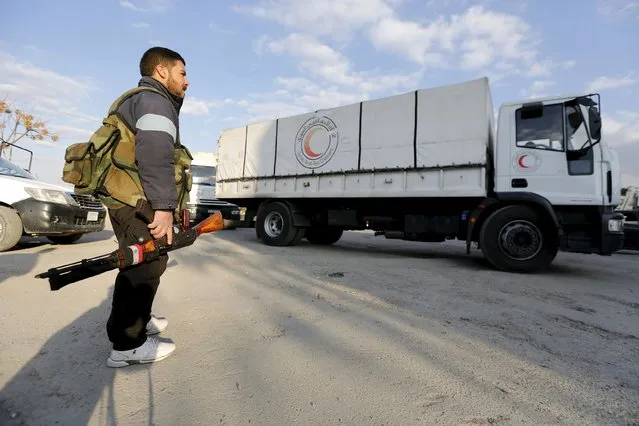 A fighter loyal to Syria's president Bashar al-Assad stands by as an aid convoy of the Syrian Arab Red Crescent enters the Wafideen Camp, which is controlled by Syrian government forces, to deliver aid into the rebel-held besieged Douma neighborhood of Damascus, Syria March 4, 2016. (Photo by Omar Sanadiki/Reuters)